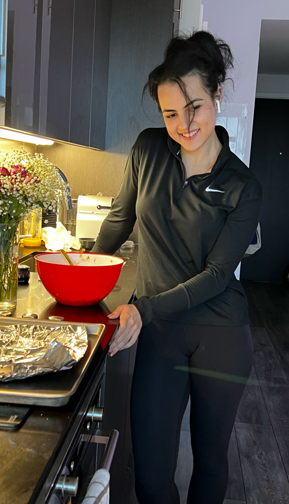 The coach stands smiling in the kitchen.